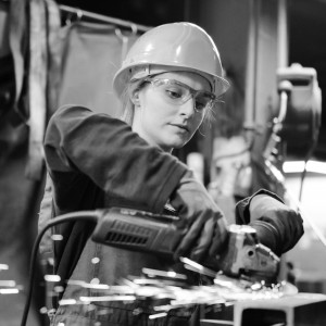 Female apprentice wearing a hard hat and safety goggles working with tools.