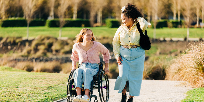 Two learners on a path one is walking and another is in a wheelchair